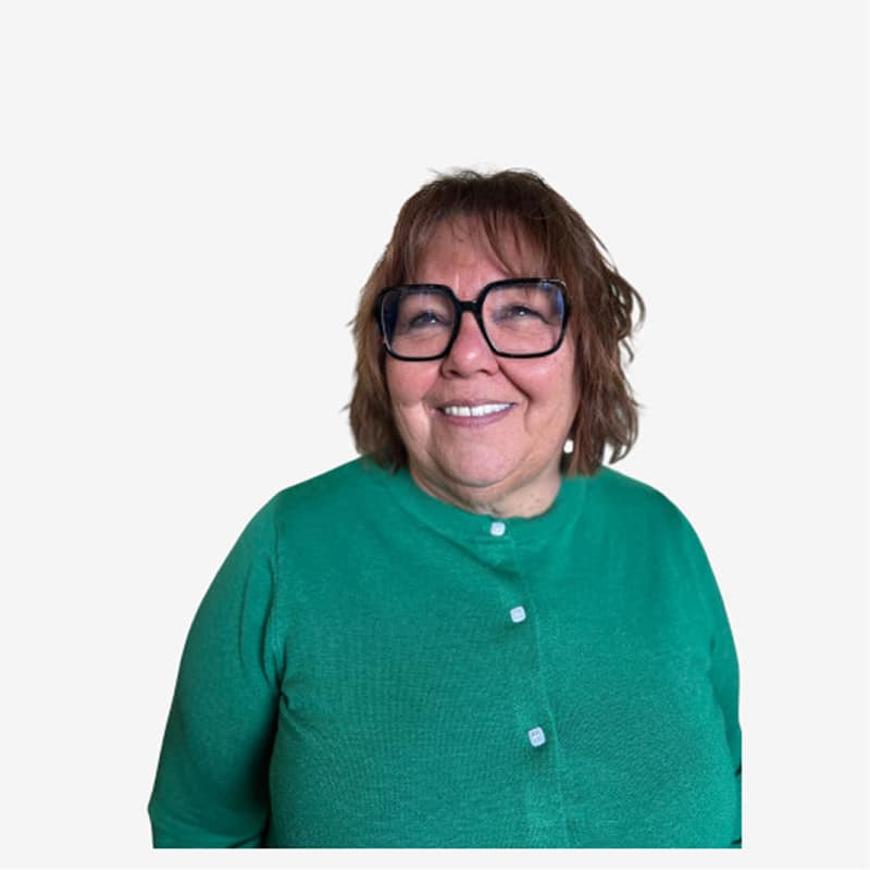 Portrait femme souriante lunettes noires gilet vert Femme souriante d'âge moyen avec des cheveux châtains courts et des lunettes noires carrées, vêtue d'un gilet vert à boutons blancs.