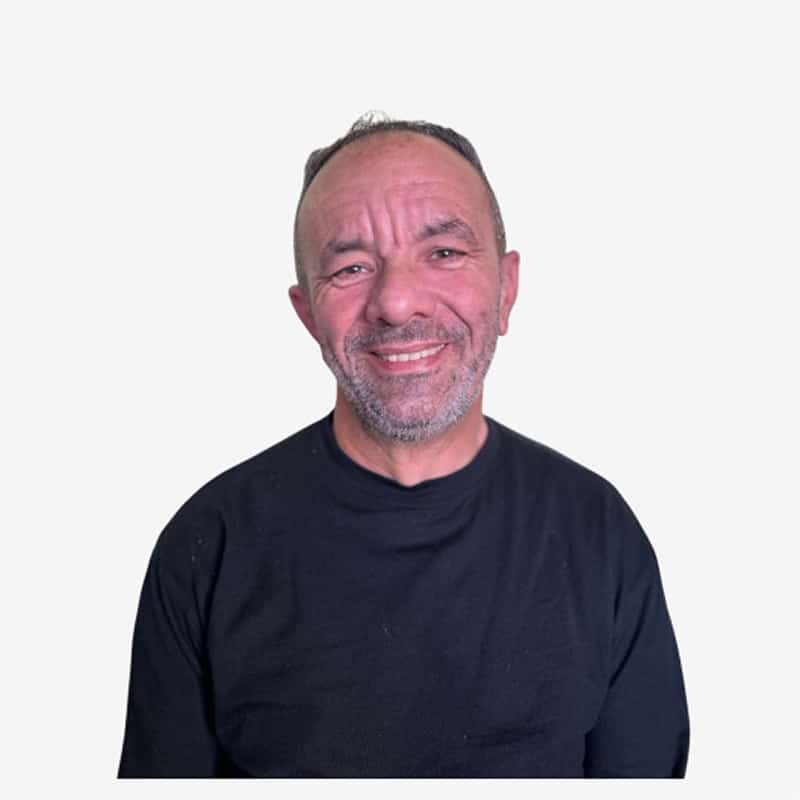 Portrait homme souriant en t-shirt noir Homme souriant d'âge moyen, avec une barbe grisonnante et des cheveux courts, portant un t-shirt noir à manches longues sur fond blanc.