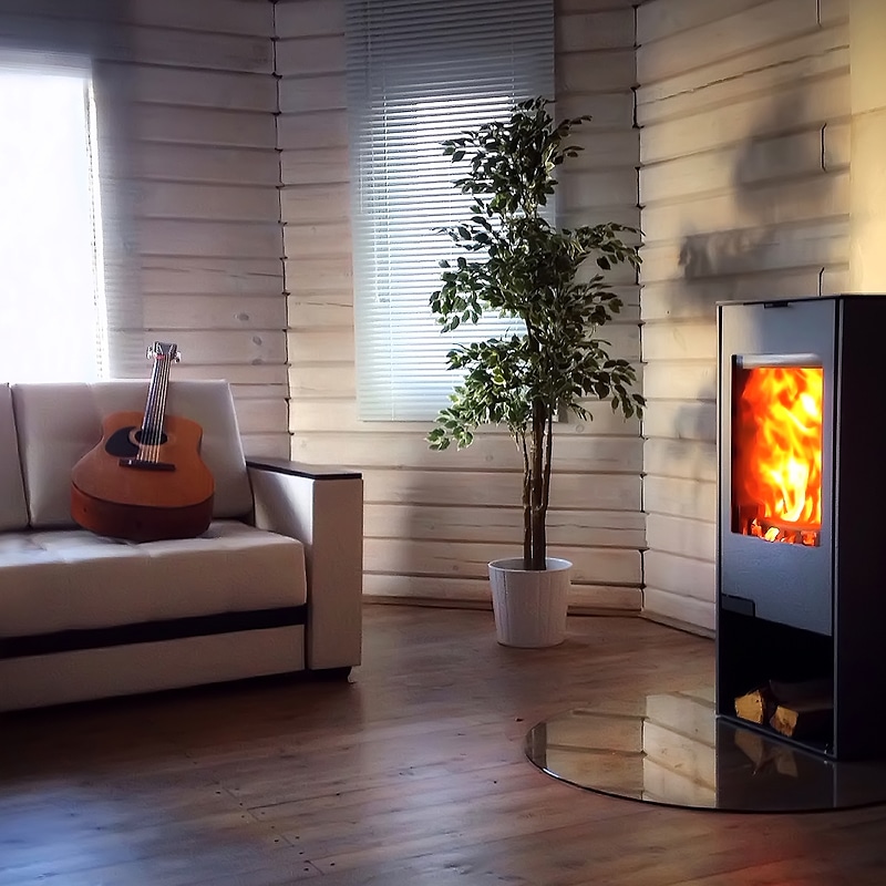 Salon cozy : poêle à bois, canapé et guitare Intérieur chaleureux d'une cabane en bois peint en blanc avec un poêle moderne en feu, un canapé, une guitare et une plante en pot.