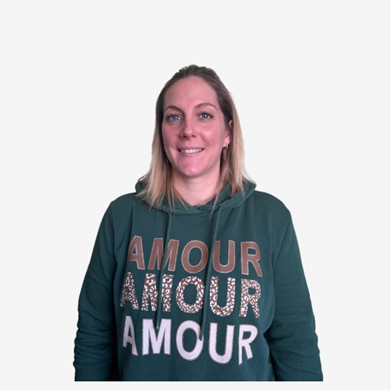 Sweat Amour Léopard Femme Vert Foncé Femme souriante avec cheveux blonds courts, vêtue d'un sweat à capuche vert foncé avec le mot "AMOUR" imprimé trois fois.